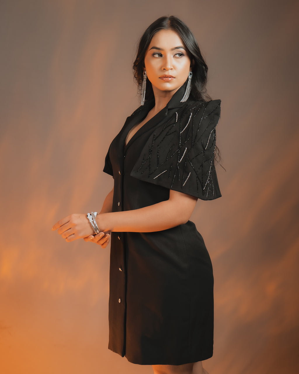 Model wearing ZEN BLAZER DRESS BLACK with embellished cape sleeves and Swarovski Crystal details.
